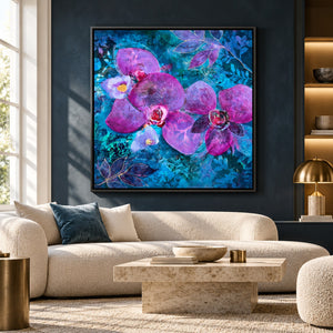 A framed wall art print featuring large purple orchids on a vivid blue and teal background, displayed above a beige sofa in a modern living room.
