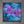 A framed square canvas art print featuring a vibrant purple orchid painting on a textured blue background, mounted on a gray concrete wall.