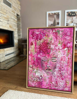 Framed pink abstract artwork with floral and face-like designs in a living room setting.