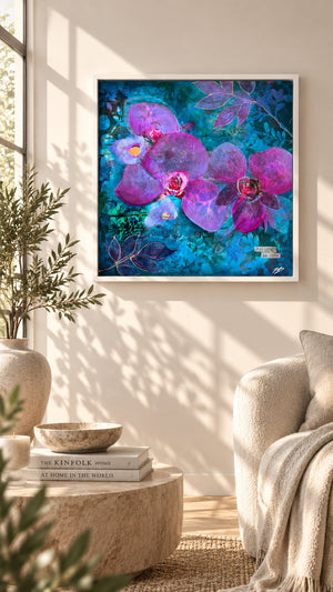 A framed square wall art print featuring large purple orchids and dragonflies on a vivid blue background, displayed in a styled living room above a sofa and next to a window.