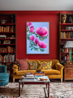 Luxury magnolia canvas print with soft pink flowers displayed on a bold red wall in a stylish living room with a sofa and bookshelves