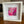 A white square framed art print with a white mat, featuring an abstract pink and magenta botanical design, displayed on a wooden table.
