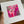A hand holds a large white matted art print featuring an abstract painting with vibrant pink, magenta, and white leaf-like patterns and textured brushstrokes.