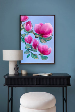 Luxury magnolia canvas print with soft pink flowers displayed on a blue wall above a console table in an elegant, feminine interior
